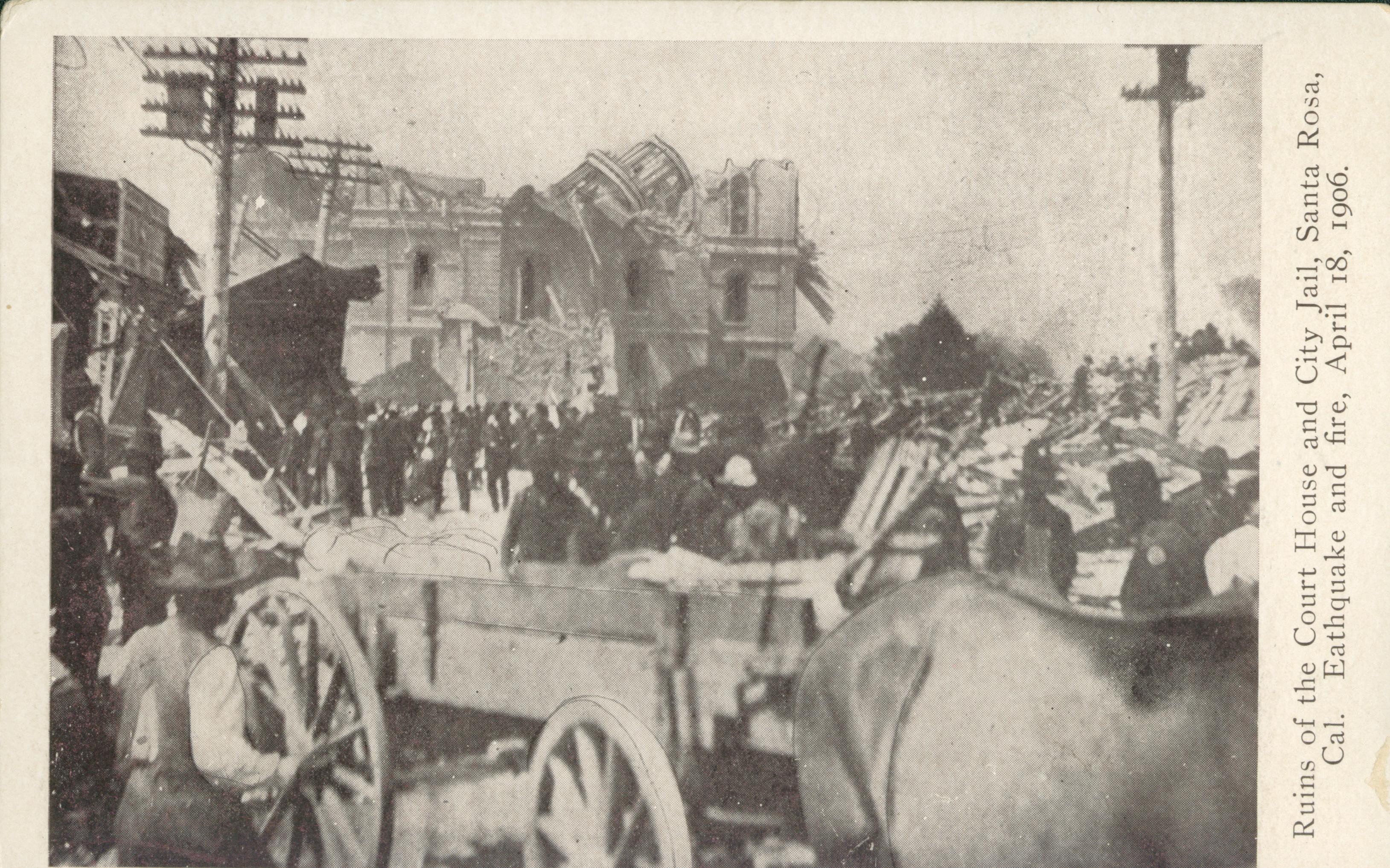 Shows the collapsed courthouse and jail with several people and carts in the foreground